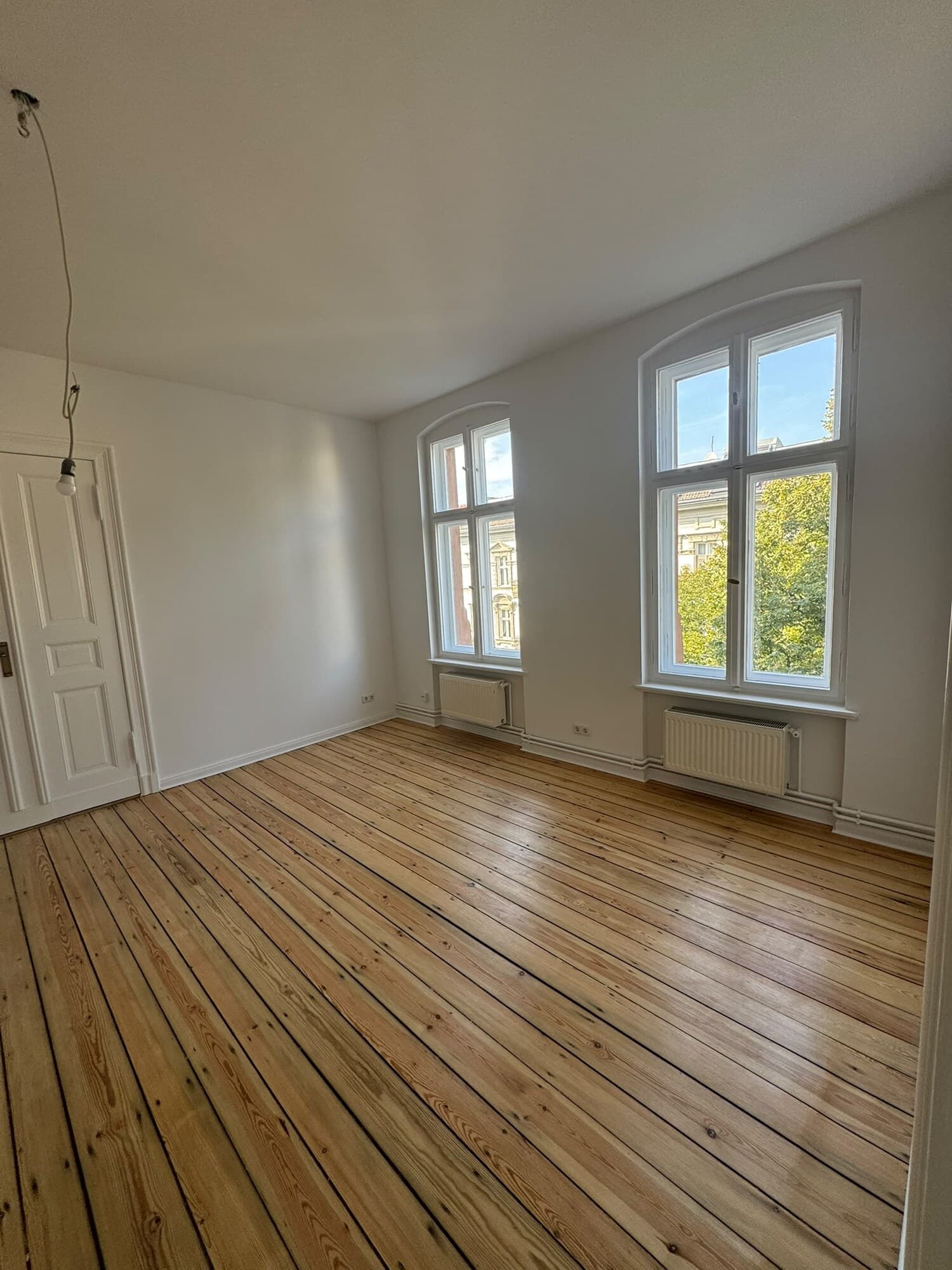 Altbauzimmer mit zwei Rundbogenfenstern und Kieferdielen