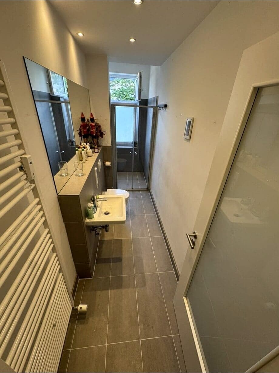 Saniertes Bad mit Dusche hinter Glasabtrennung und Handtuchheizkörper