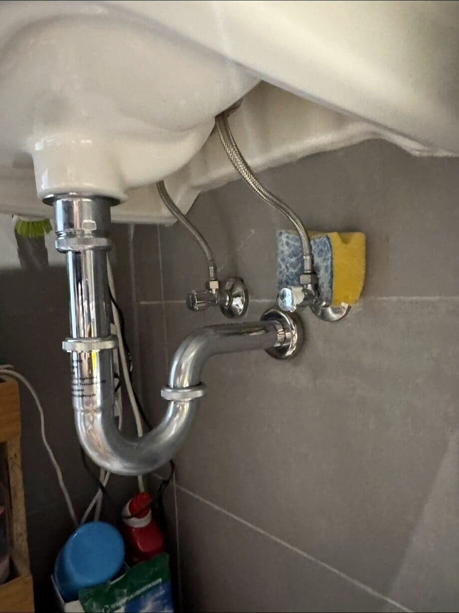 Neuer Siphon mit Eckventilen und Anschlussschläuchen unter dem Waschtisch