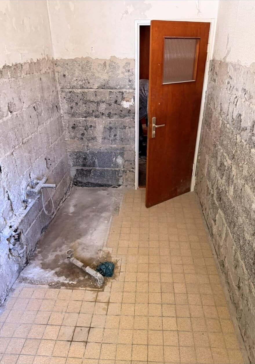 Bad im Rückbau: Fliesen bis auf das Mauerwerk entfernt, Wanne ausgebaut